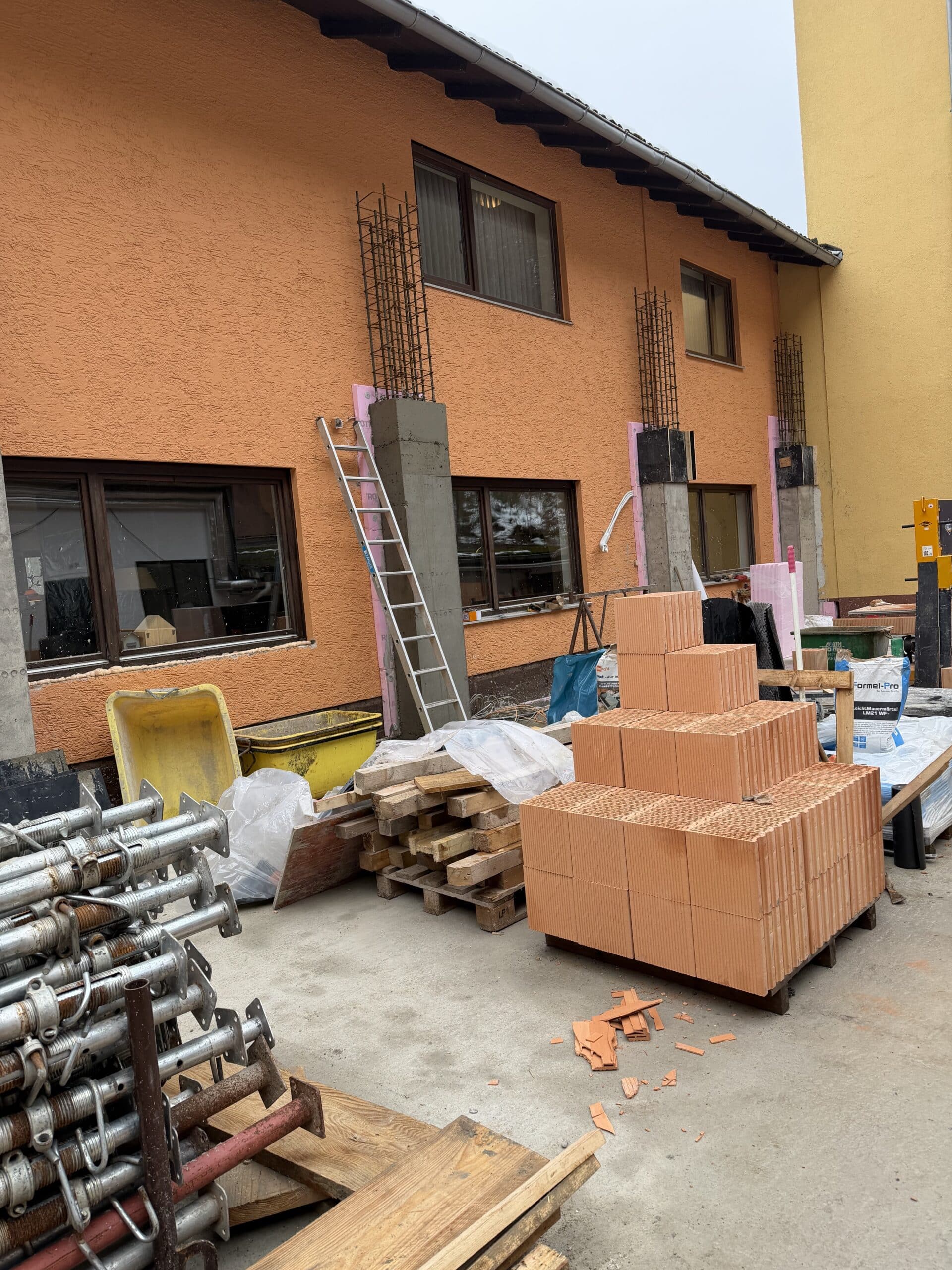 Renovierung Waldhotel Heppe - Außenfassade mit Baumaterialien während Umbauphase