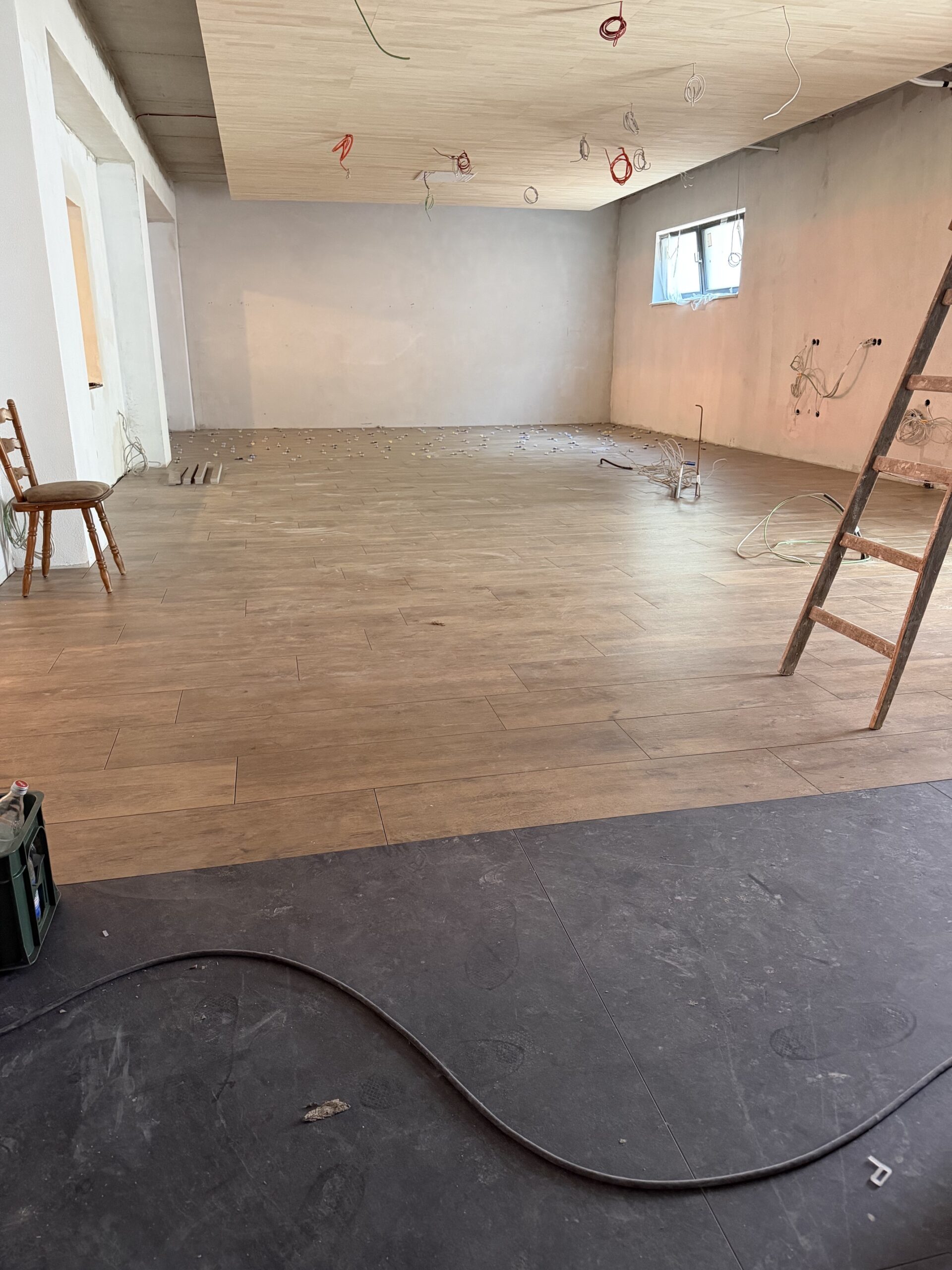 Neuer Holzfliesenboden im Umbau-Bereich des Waldhotel Heppe – Rohbauphase mit verputzten Wänden, Elektroinstallationen an der Decke und Baugerüst