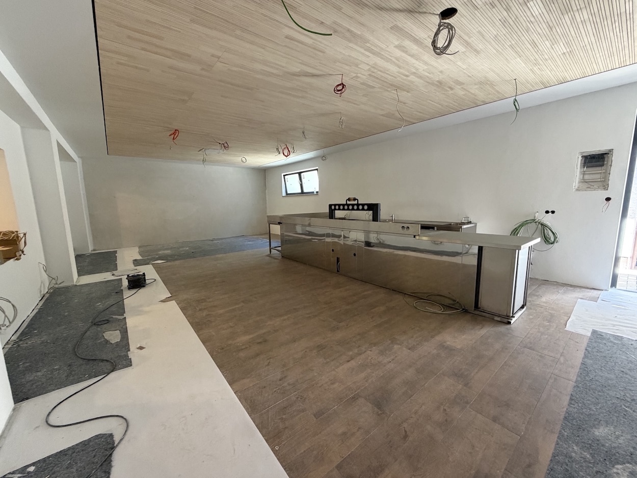 Neuer Frühstücksraum im Umbau des Waldhotel Heppe: Holzoptik-Fliesenboden, Holzdecke und Edelstahl-Buffettheke bereits installiert, Elektroinstallationen noch sichtbar