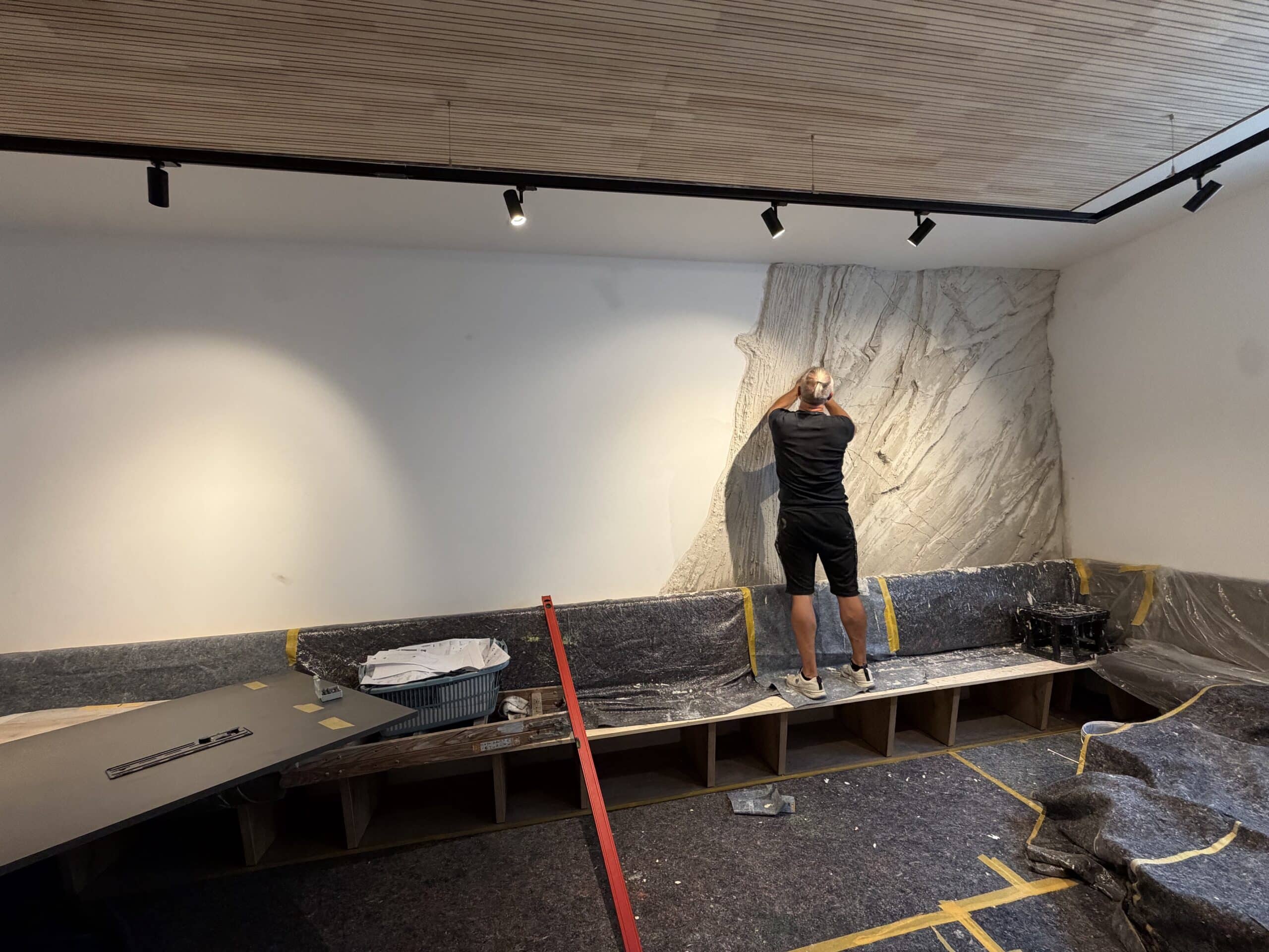 Handwerker gestaltet dekorative Felswand-Struktur in gips-ähnlicher Optik im neuen Frühstücksraumes des Waldhotel Heppe während der Bauphase