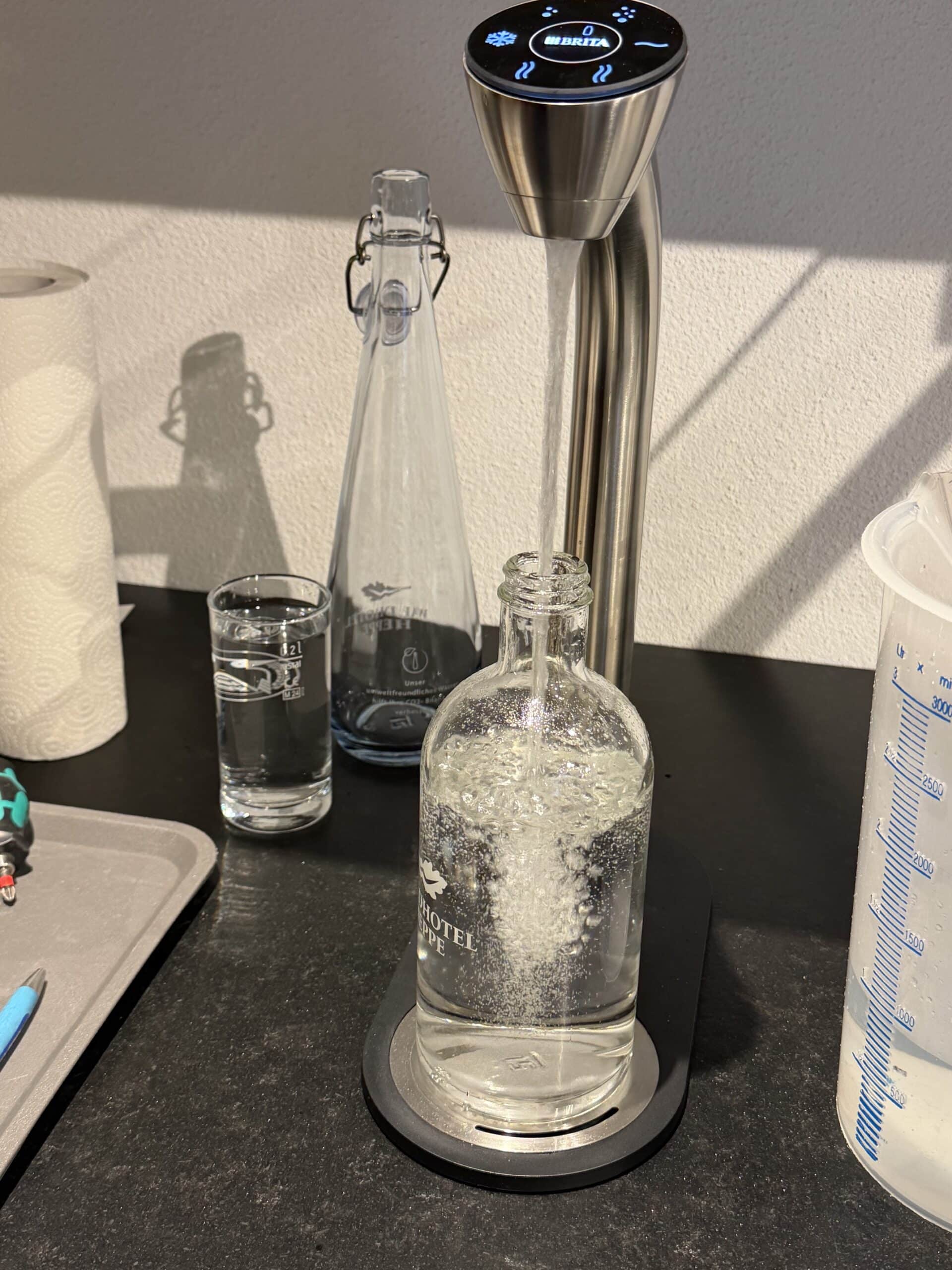 Edelstahl-Wassersprudler von Brita befüllt Glasflasche mit Waldhotel-Heppe-Branding mit spritzigem Mineralwasser
